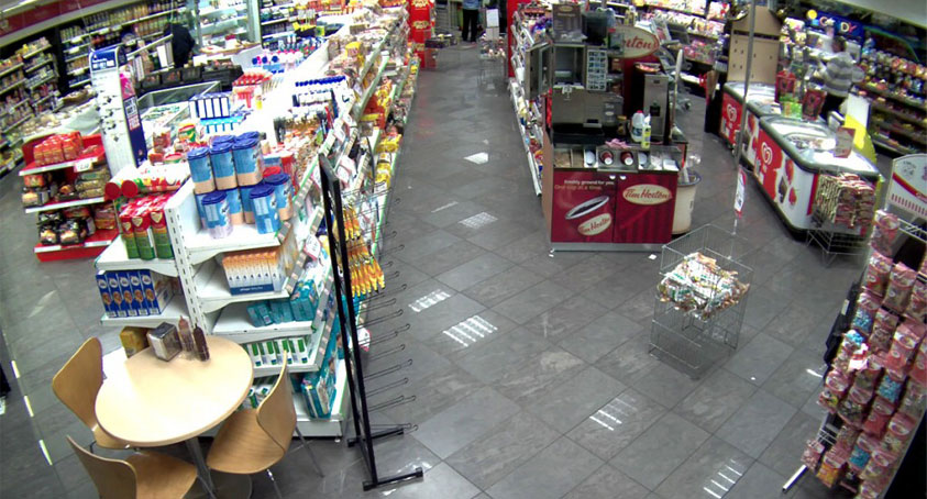 A security cam photo of a gas station interior aisle and coffee bar.