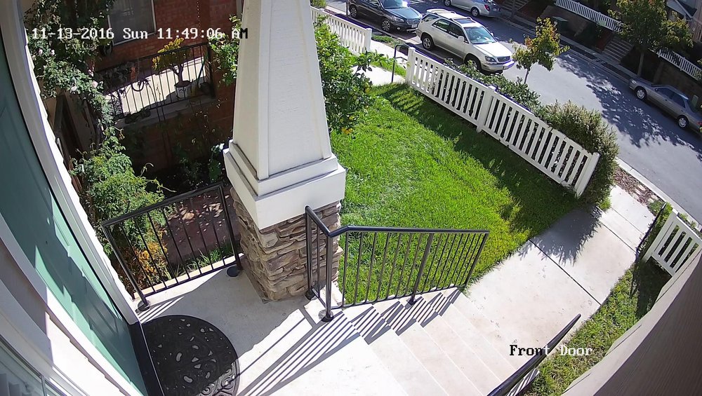 A home security camera photo of a front door, stairs, and sidewalk.