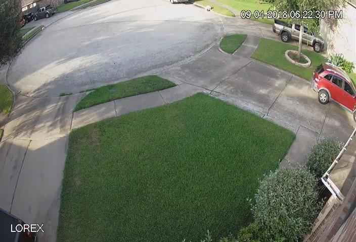 A home security camera photo a front yard, driveway and cul-de-sac.